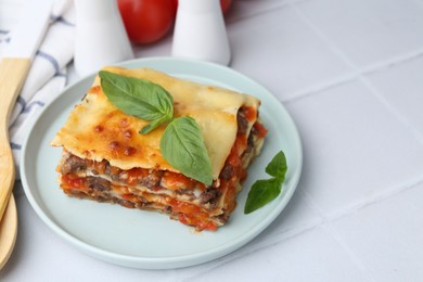 Photo of Delicious cooked lasagna with basil on white tiled table, closeup. Space for text