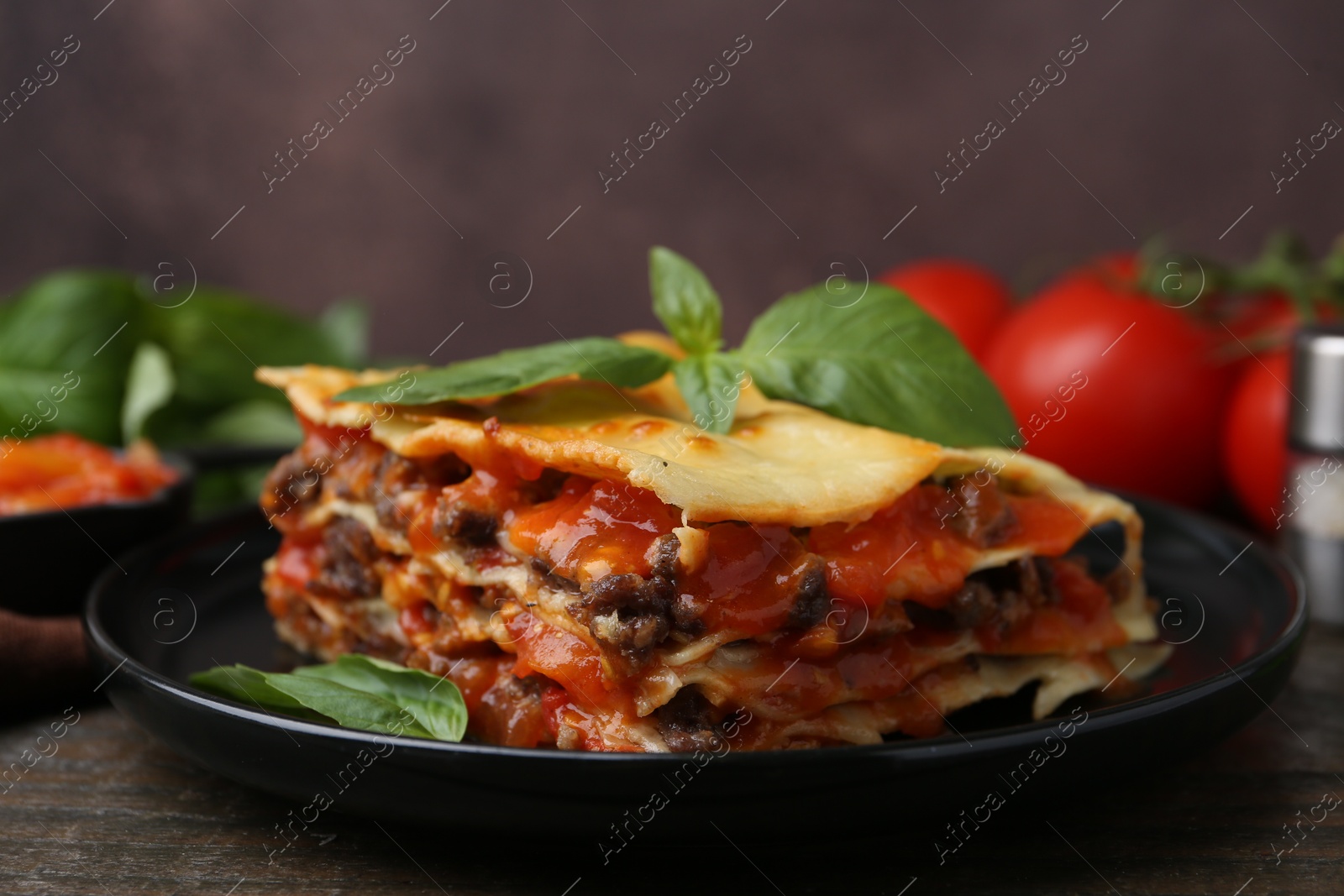 Photo of Delicious cooked lasagna with basil on wooden table, closeup