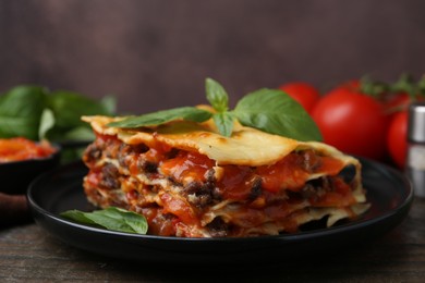 Delicious cooked lasagna with basil on wooden table, closeup