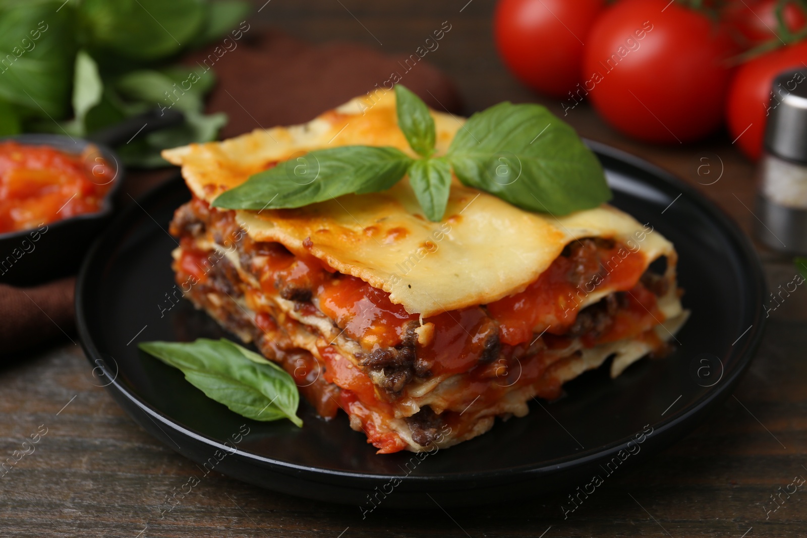 Photo of Delicious cooked lasagna with basil on wooden table, closeup