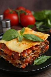 Delicious cooked lasagna with basil on wooden table, closeup