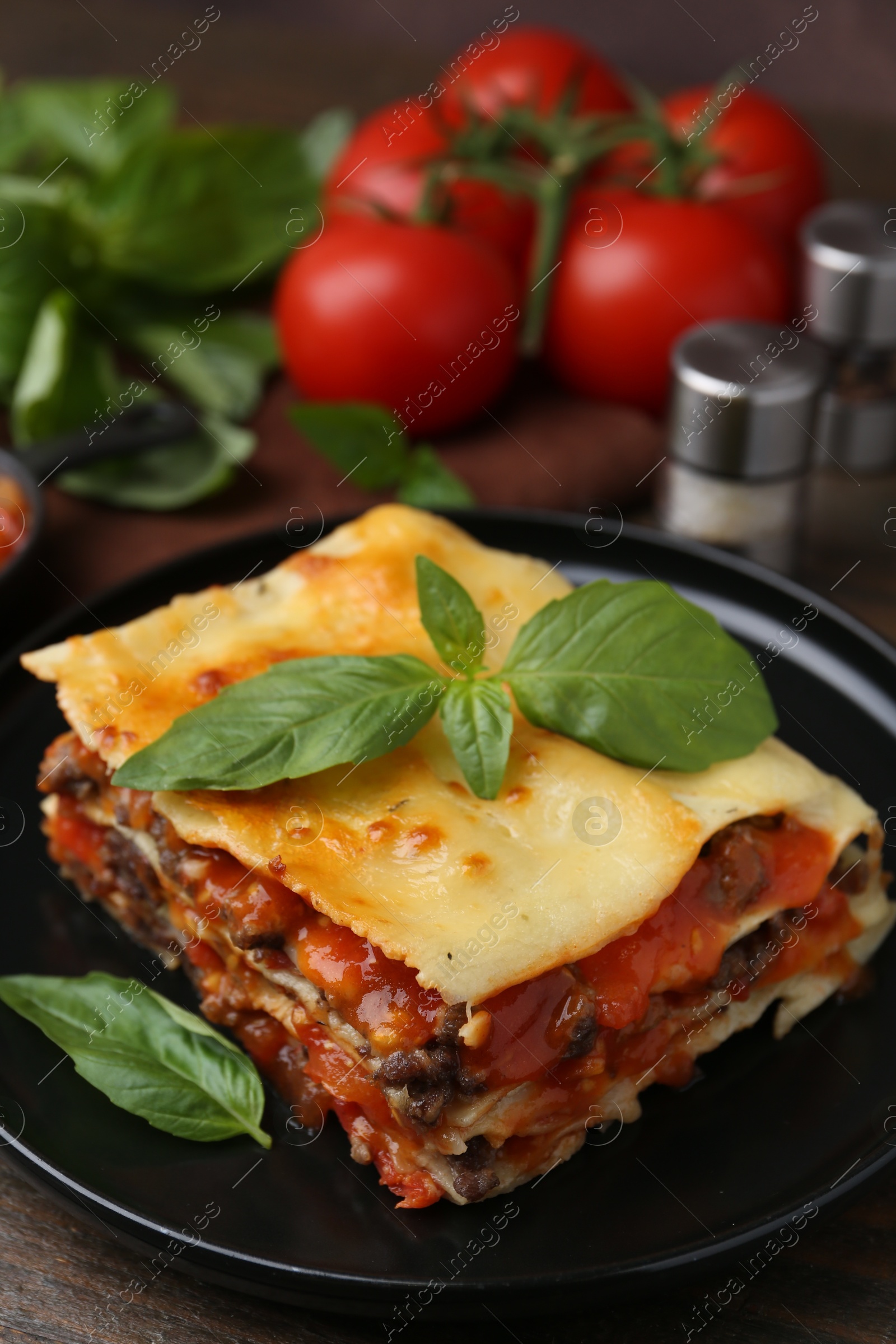 Photo of Delicious cooked lasagna with basil on wooden table, closeup