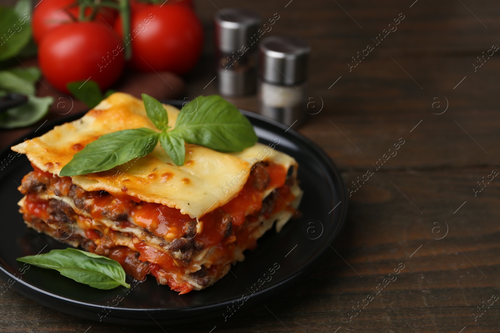 Photo of Delicious cooked lasagna with basil on wooden table, closeup. Space for text