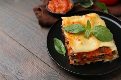 Photo of Delicious cooked lasagna with basil on wooden table, closeup. Space for text