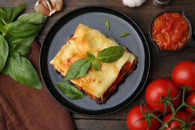 Delicious cooked lasagna and ingredients on wooden table, flat lay