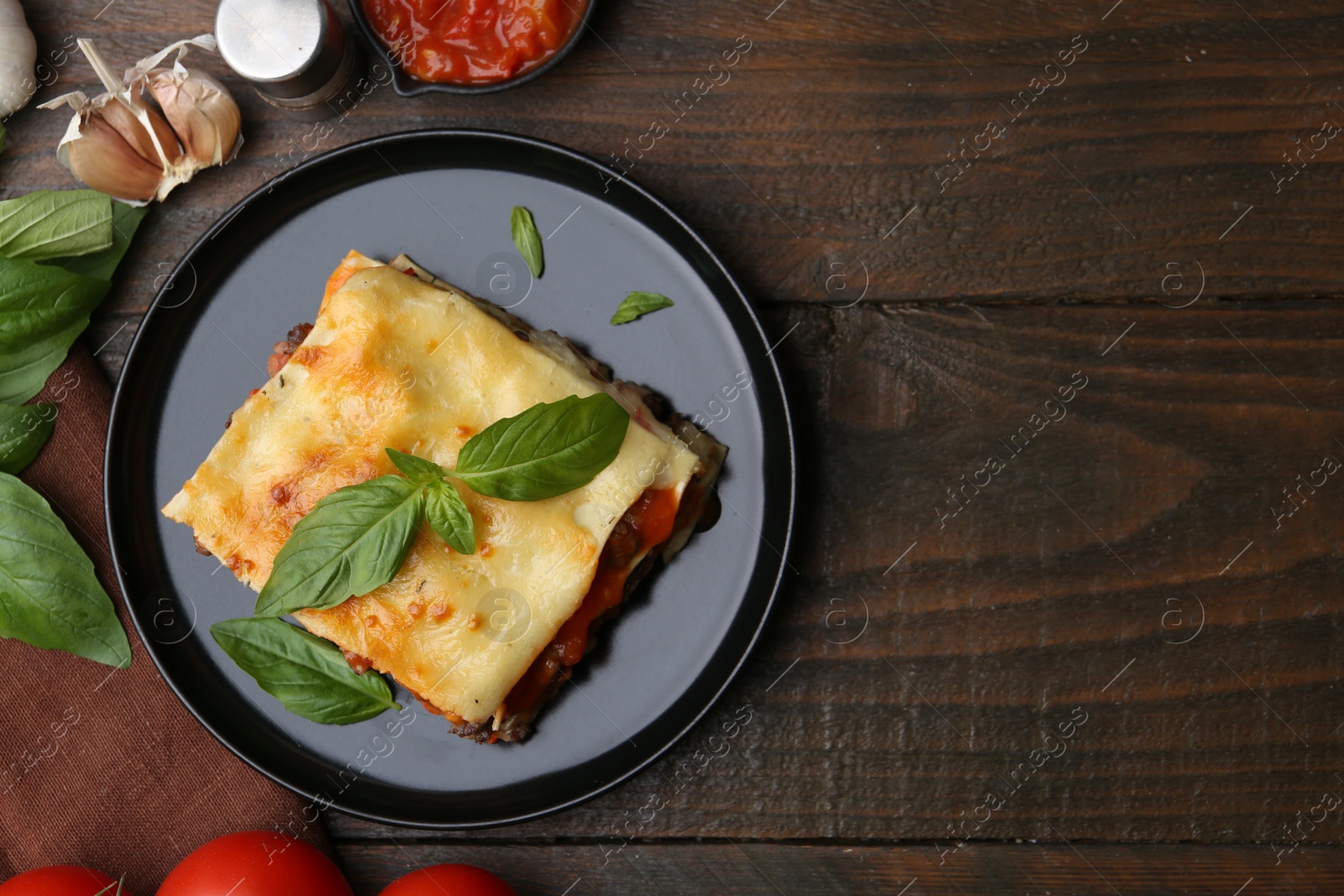 Photo of Delicious cooked lasagna and ingredients on wooden table, flat lay. Space for text