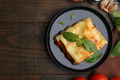 Photo of Delicious cooked lasagna and ingredients on wooden table, flat lay. Space for text