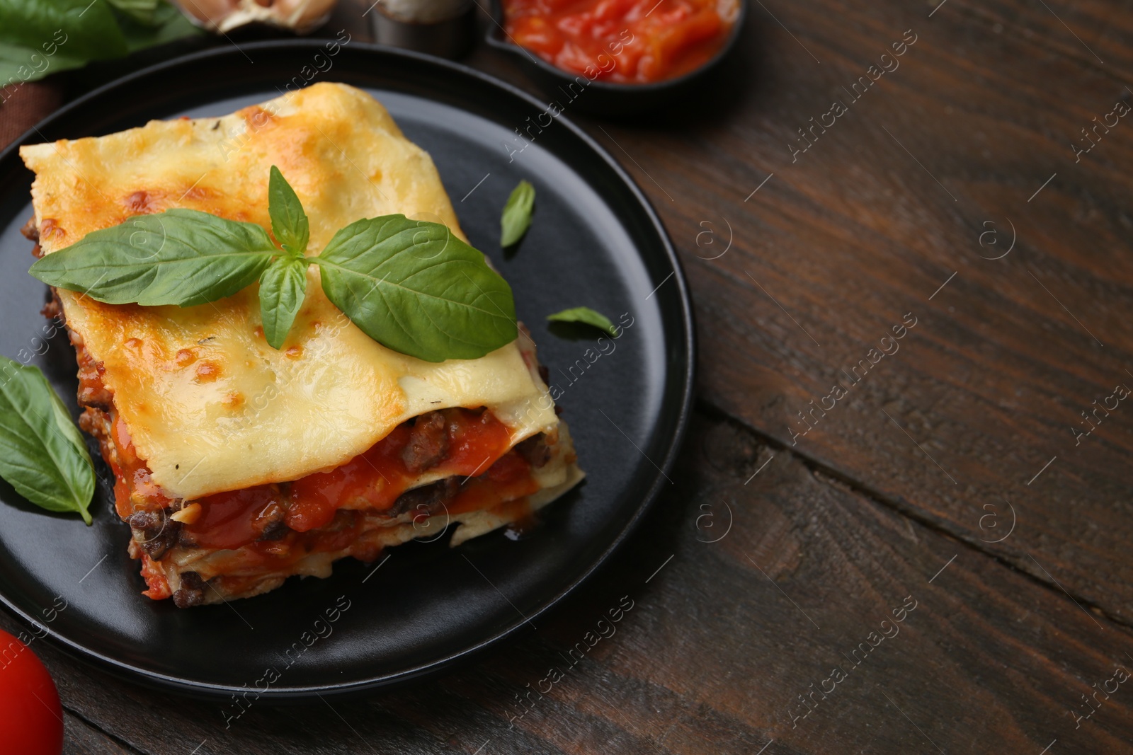 Photo of Delicious cooked lasagna with basil on wooden table, closeup. Space for text