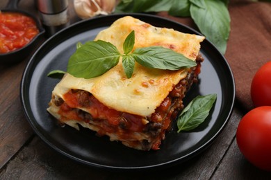 Photo of Delicious cooked lasagna with basil on wooden table, closeup