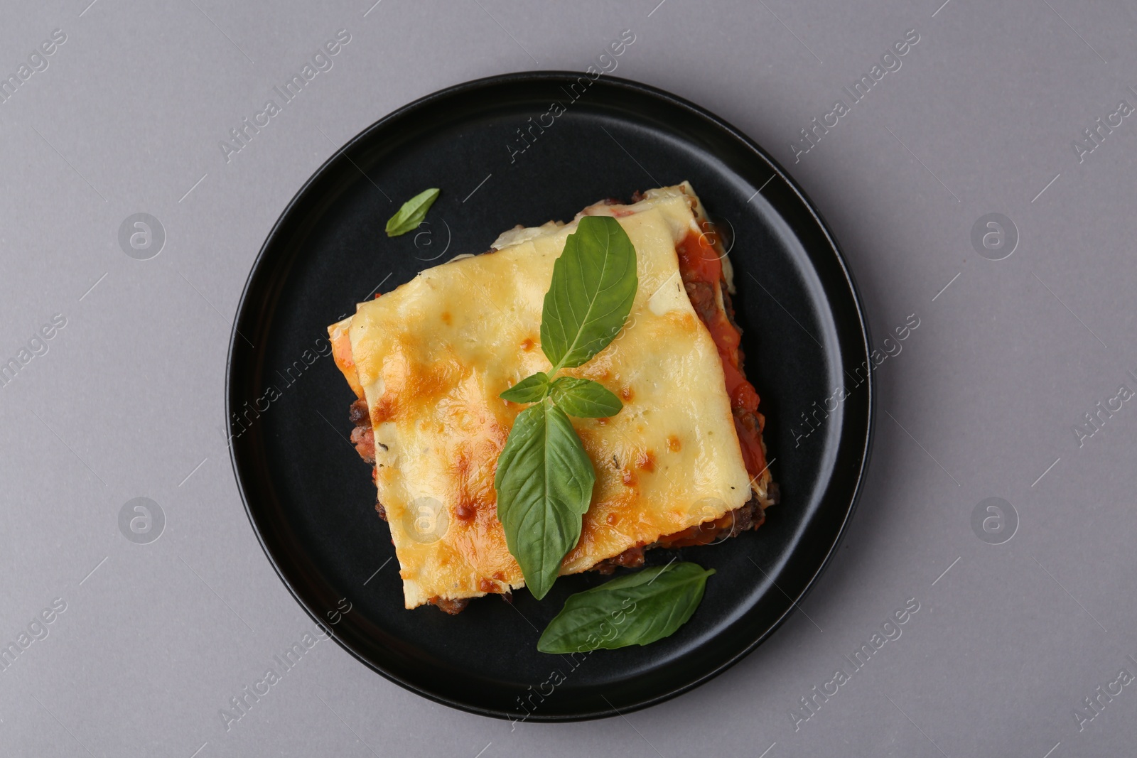 Photo of Delicious cooked lasagna with basil on grey table, top view