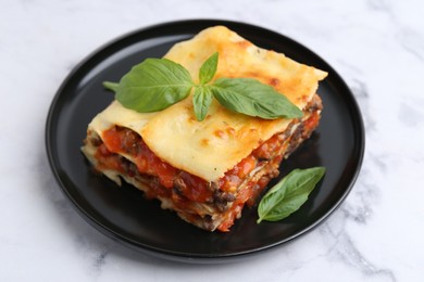 Photo of Delicious cooked lasagna with basil on white marble table, closeup