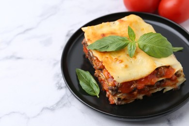 Photo of Delicious cooked lasagna with basil on white marble table, closeup. Space for text