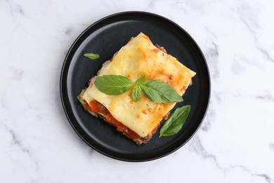 Photo of Delicious cooked lasagna with basil on white marble table, top view