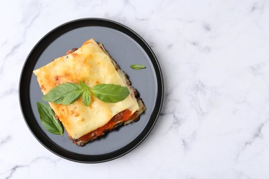 Photo of Delicious cooked lasagna with basil on white marble table, top view. Space for text