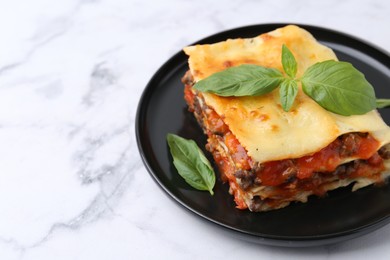 Photo of Delicious cooked lasagna with basil on white marble table, closeup. Space for text