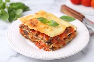 Photo of Delicious cooked lasagna with basil on white marble table, closeup