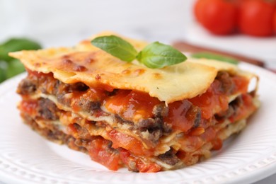 Photo of Delicious cooked lasagna with basil on plate, closeup