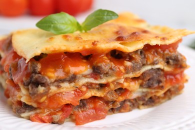 Photo of Delicious cooked lasagna with basil on plate, closeup