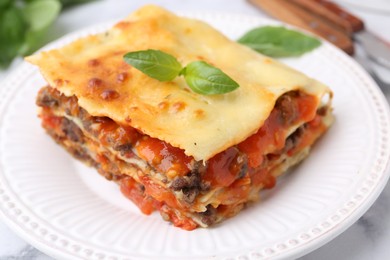 Photo of Delicious cooked lasagna with basil on table, closeup