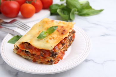 Photo of Delicious cooked lasagna with basil served on white marble table, closeup