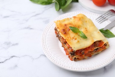 Photo of Delicious cooked lasagna with basil served on white marble table, closeup. Space for text