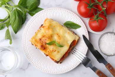 Photo of Delicious cooked lasagna with basil served on white marble table, flat lay