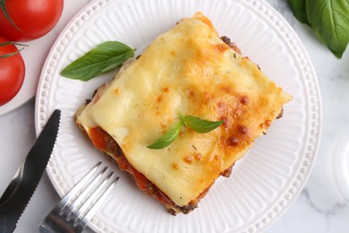 Delicious cooked lasagna with basil served on white marble table, flat lay