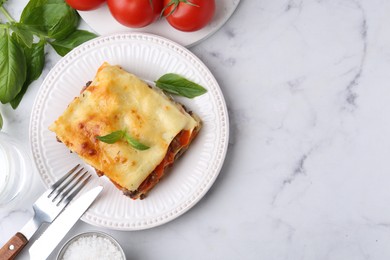 Photo of Delicious cooked lasagna with basil served on white marble table, flat lay. Space for text