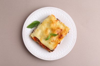 Delicious cooked lasagna with basil on light grey table, top view