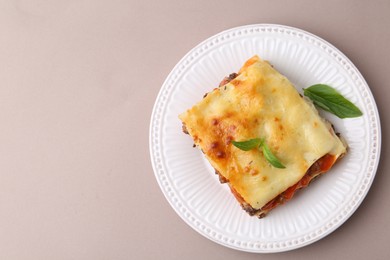 Photo of Delicious cooked lasagna with basil on light grey table, top view. Space for text