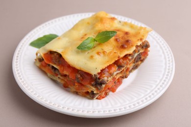 Photo of Delicious cooked lasagna with basil on light grey table, closeup