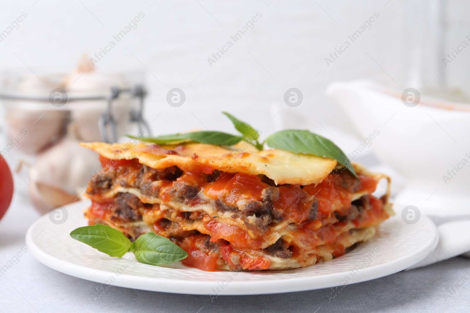 Photo of Delicious cooked lasagna with basil on light table, closeup