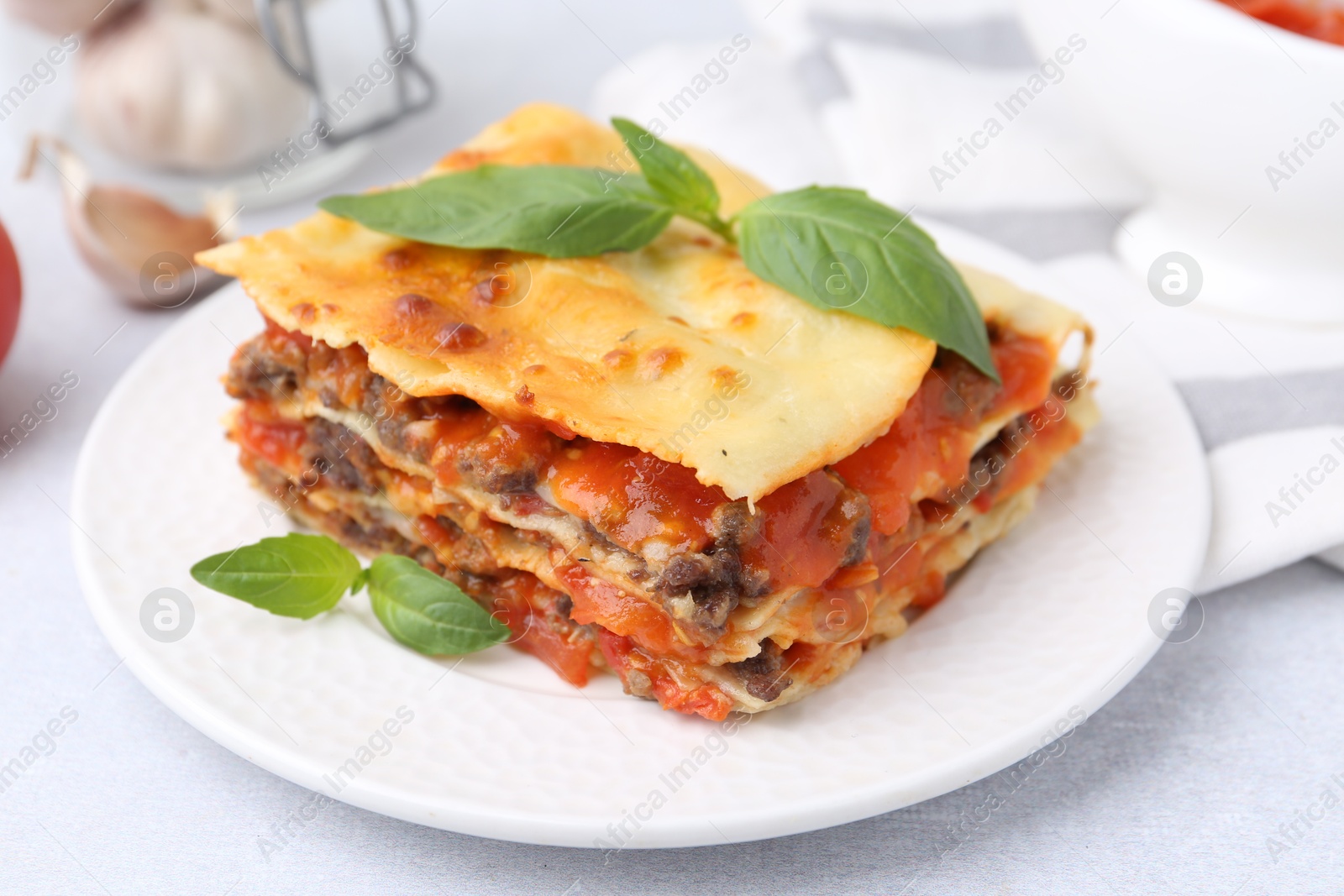 Photo of Delicious cooked lasagna with basil on light table, closeup