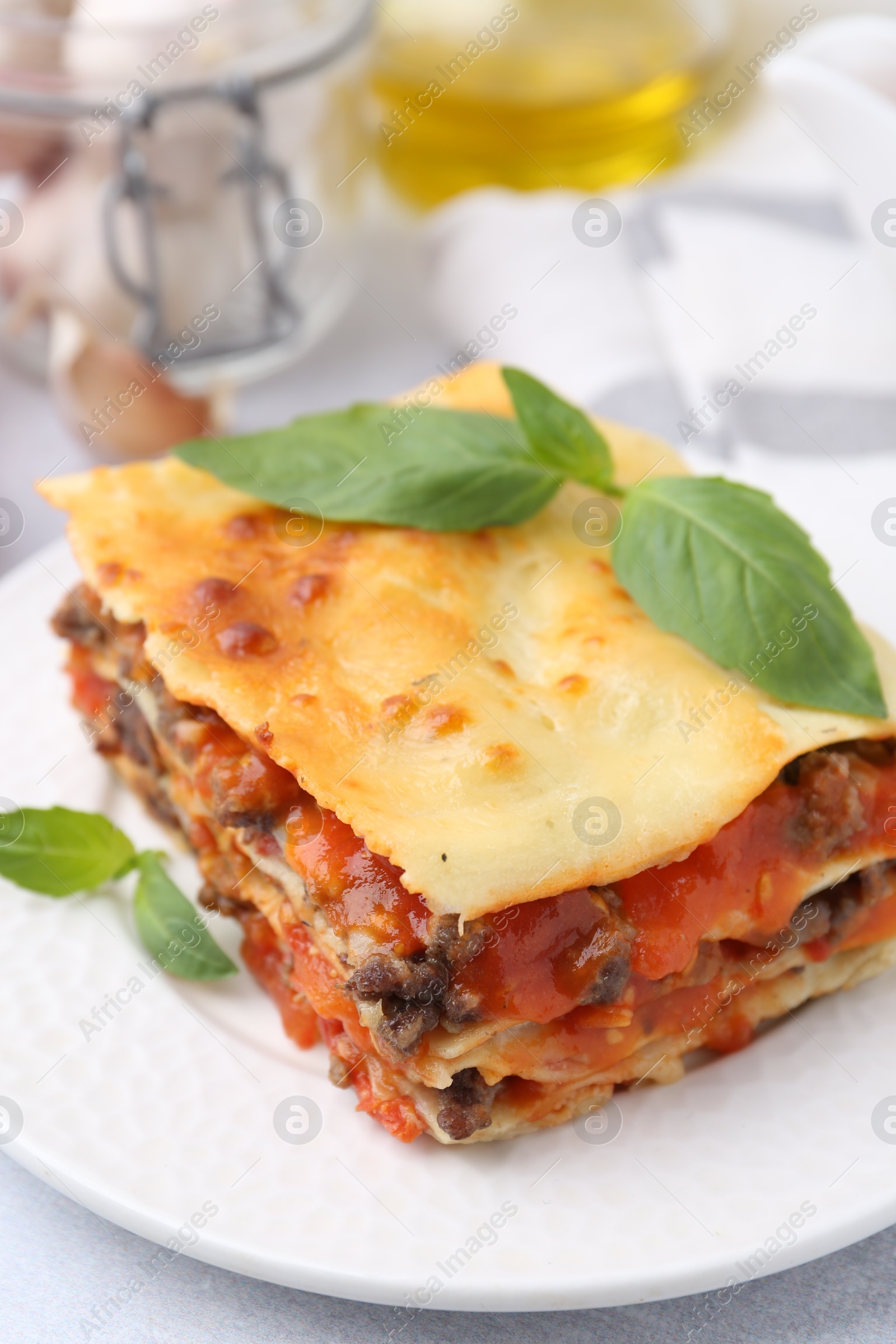 Photo of Delicious cooked lasagna with basil on light table, closeup