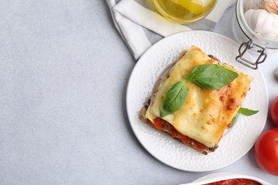 Photo of Delicious cooked lasagna and ingredients on light table, flat lay. Space for text