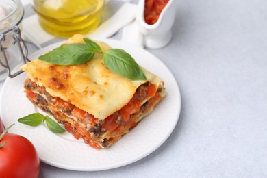 Photo of Delicious cooked lasagna and ingredients on light table, closeup. Space for text