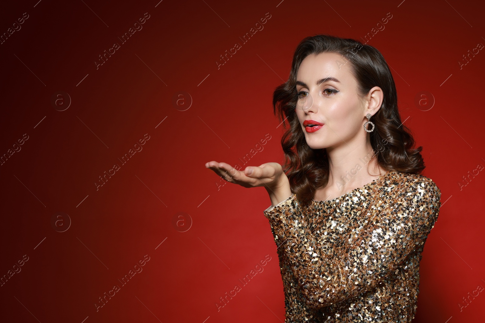 Photo of Woman with perfect makeup sending air kiss on red background. Space for text