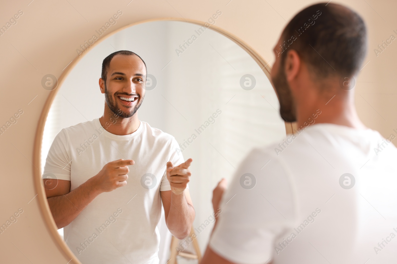 Photo of Smiling man looking at mirror in bathroom