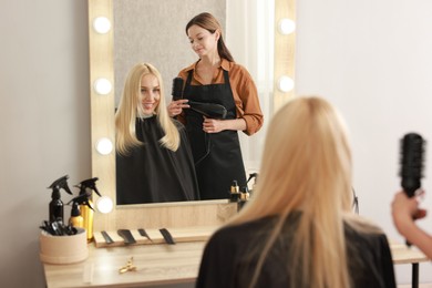 Photo of Hair cutting. Professional hairdresser working with client in salon, selective focus