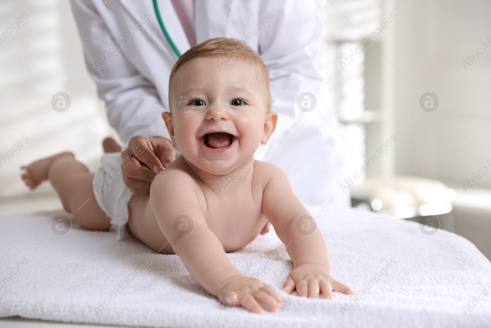 Photo of Pediatrician examining little child with stethoscope in clinic, closeup. Checking baby's health