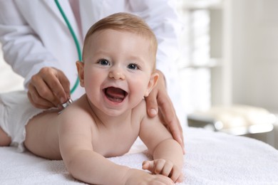 Photo of Pediatrician examining little child with stethoscope in clinic, closeup. Checking baby's health