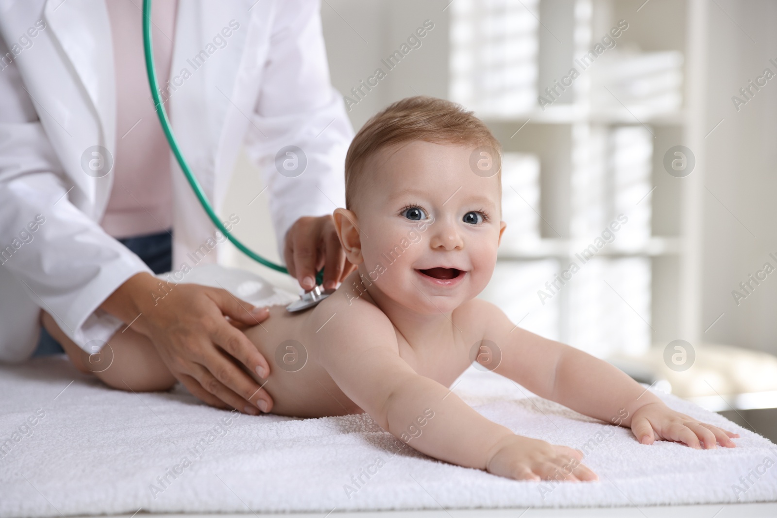 Photo of Pediatrician examining little child with stethoscope in clinic, closeup. Checking baby's health