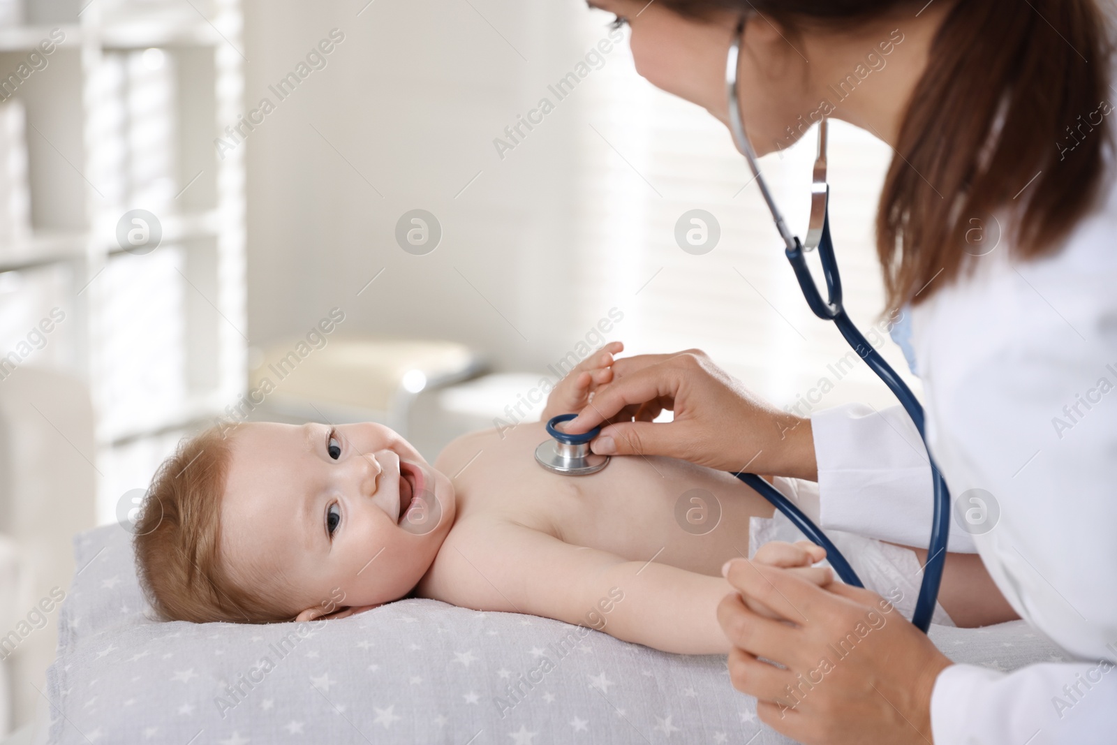 Photo of Pediatrician examining little child with stethoscope in clinic. Checking baby's health