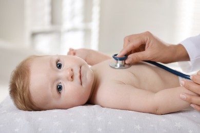 Photo of Pediatrician examining little child with stethoscope in clinic, closeup. Checking baby's health