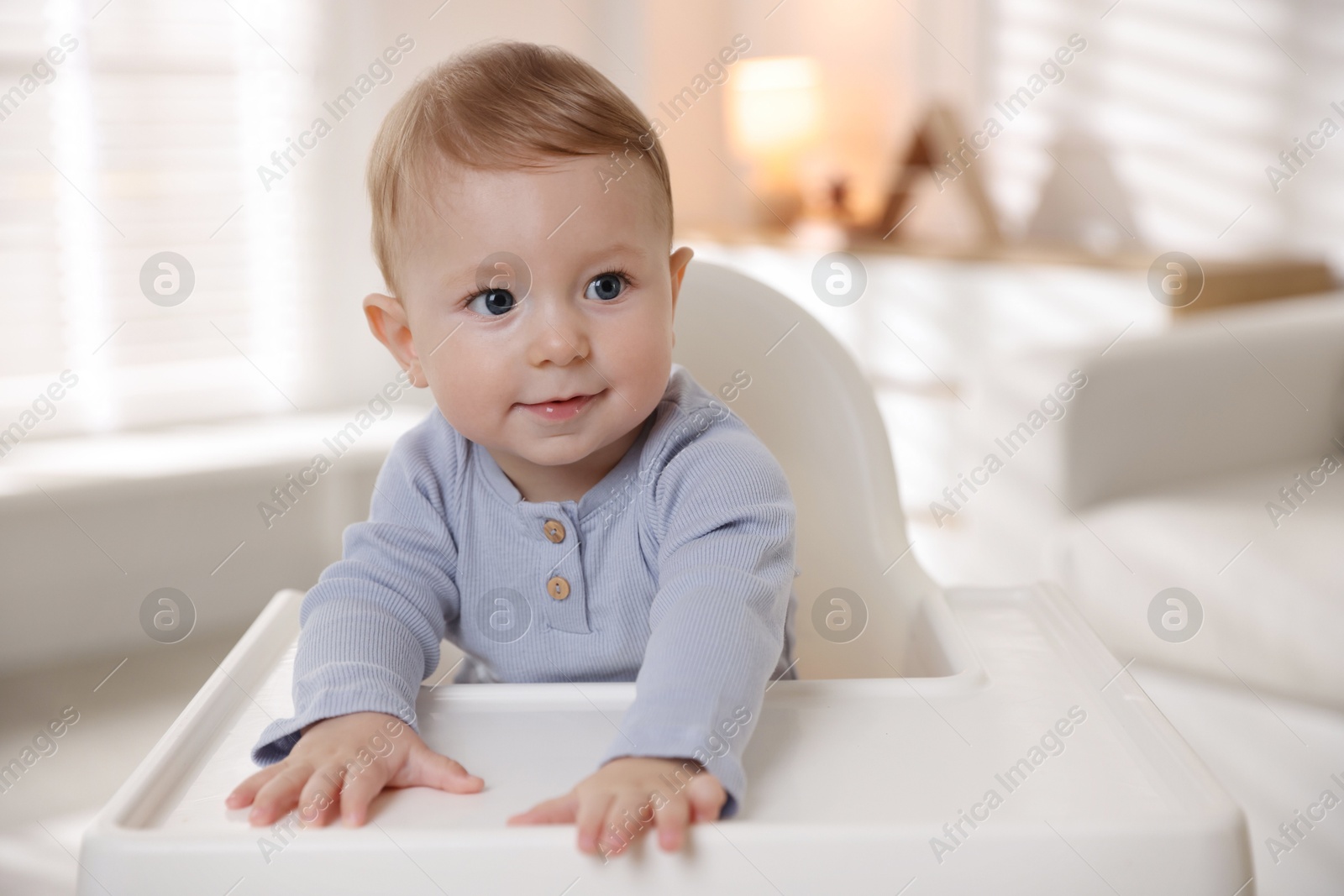 Photo of Cute little baby in high chair indoors