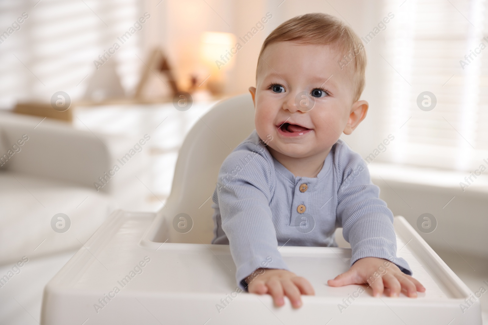 Photo of Cute little baby in high chair indoors