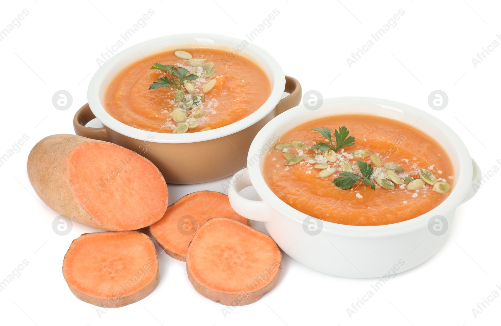 Photo of Delicious sweet potato soup with pumpkin seeds in bowls and fresh vegetable isolated on white