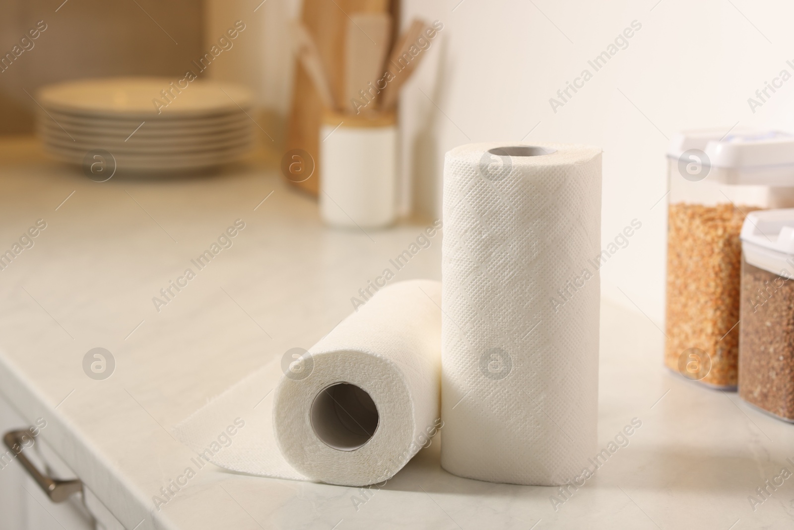 Photo of Rolls of paper towels on white countertop in kitchen, space for text