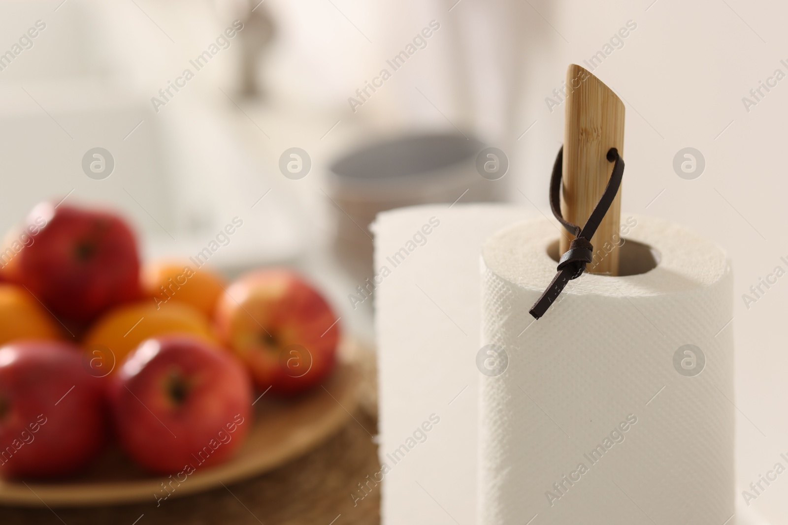 Photo of Roll of paper towels and fruits in kitchen, closeup. Space for text