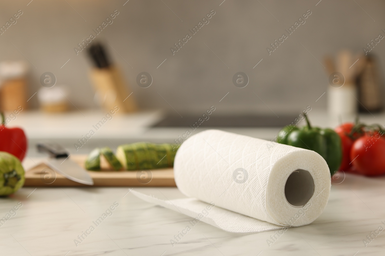 Photo of Roll of paper towels and vegetables on white marble table in kitchen, closeup. Space for text